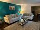 Living room boasts teal accent wall, beige sofas, and dark hardwood floors at 5595 Stagecoach Rd, Rex, GA 30273