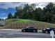 Street view of new construction with landscaped hillside and modern black vehicles parked on the asphalt at 5015 Renvyle Dr. (Lot 12) Dr, Atlanta, GA 30339