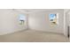 Spacious bedroom featuring neutral carpet, two windows providing natural light, and clean, neutral-toned walls at 8593 Preakness Pass, Lithonia, GA 30058