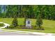 Welcoming community entrance featuring a stone sign, ornamental trees, and manicured landscape at 8593 Preakness Pass, Lithonia, GA 30058