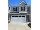 A two-story home featuring a prominent white garage door, stone accents, and gray siding at 308 Elgin Dr, Lawrenceville, GA 30045