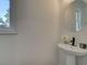 Small powder room with pedestal sink, oval mirror, and single window at 1996 Deco Dr, Kennesaw, GA 30144