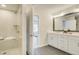 Bright bathroom with a glass shower and vanity with a large mirror and white cabinets at 1980 Deco Dr, Kennesaw, GA 30144