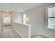 Upstairs hallway with wood floors, light paint, and a window with a view into another room at 1980 Deco Dr, Kennesaw, GA 30144