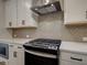 Close up view of the kitchen with white cabinets, stainless steel appliances, herringbone backsplash, and quartz countertops at 1980 Deco Dr, Kennesaw, GA 30144