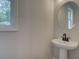 Half bathroom features a pedestal sink, a round mirror, a window and neutral walls at 1988 Deco Dr, Kennesaw, GA 30144