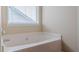 Bathtub with a window with blinds and tile surround at 1623 Bradmere Ln, Lithia Springs, GA 30122