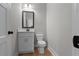 Small half bathroom with white vanity, marble countertop, and toilet at 136 Rainey Rd, Temple, GA 30179