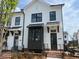 New construction townhome featuring a white facade, black window frames, and brick base at 630 Skytop Dr # 157, Cumming, GA 30040