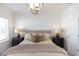 Bedroom featuring a brick accent wall, modern chandelier, side tables with lamps, and a large window at 621 Silva St # 124, Cumming, GA 30040