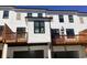 Rear exterior view of modern townhomes featuring white siding, black trim, garages, and wooden balconies at 621 Silva St # 124, Cumming, GA 30040