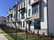 Modern townhouses with white brick, black windows, and fenced yards at 631 Silva St # 129, Cumming, GA 30040