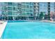 Large community swimming pool surrounded by lounge chairs and greenery, with a modern building in the background at 923 Peachtree Ne St # 1527, Atlanta, GA 30309