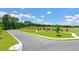 A curved street bordered by green grass and small decorative trees under a bright sky at 8588 Seabiscuit Rd, Lithonia, GA 30058