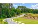 A winding street with lush green trees, landscaping, and a glimpse of open fields at 8588 Seabiscuit Rd, Lithonia, GA 30058