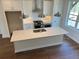 Bright kitchen featuring a large island, white cabinets, stainless appliances, and hardwood floors at 629 Silva St # 128, Cumming, GA 30040