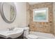 Well-lit bathroom with tiled walls, a vanity with sink, toilet, and bathtub with shower at 2121 Arlington Ne Ave, Atlanta, GA 30324