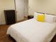 Cozy bedroom with hardwood floors, white bedding, a yellow throw pillow, and a dark dresser at 2121 Arlington Ne Ave, Atlanta, GA 30324