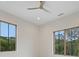 Bright bedroom with two large windows overlooking a lush, green landscape and a contemporary ceiling fan at 8200 Main St # 1206, Woodstock, GA 30188