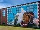 Exterior wall mural featuring a black aviator holding a toy plane with 'Dream high!' painted on the wall at 3324 Springhaven Ave, Atlanta, GA 30354