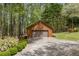 Detached garage with natural colored siding and a well-manicured lawn, nestled among mature trees at 3208 Paddock Rd, Covington, GA 30014
