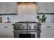 Modern kitchen features stainless steel stove with patterned backsplash and white cabinetry at 1065 Peachtree Ne St # 3003, Atlanta, GA 30309