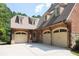 Attached three-car garage with brick and stone accents, dormer windows, and a spacious driveway at 858 Middle Fork Trl, Suwanee, GA 30024