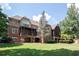 Expansive rear exterior featuring a covered patio, lush landscaping, and beautiful architecture at 858 Middle Fork Trl, Suwanee, GA 30024