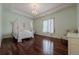 Charming bedroom with hardwood floors, canopy bed, and a sitting area at 3133 Saint Ives Country Club Pkwy, Johns Creek, GA 30097
