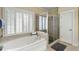 Relaxing bathroom featuring a soaking tub, a tiled shower, and shuttered windows at 216 Crescent Moon Way, Canton, GA 30114