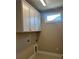 Bright laundry room featuring white cabinets, tile flooring and a window at 5225 Ginger Rose Ct, Cumming, GA 30028