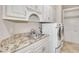Well-equipped laundry room featuring white cabinets, granite countertops, sink, and modern washer/dryer units at 2867 Darlington Run, Duluth, GA 30097