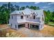 A partially completed two-story home features a three-car garage with mature trees in the background at 2675 Drayton Hall Dr, Buford, GA 30519
