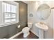 Stylish powder room featuring a pedestal sink, toilet, and a modern round mirror at 550 Whitlox Nw Rd, Atlanta, GA 30318