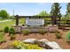Welcome sign at The Courtyards of Franklin Goldmine entrance surrounded by landscaping, stone and mature trees at 5210 Ginger Rose Ct, Cumming, GA 30028