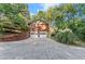 Two-car garage with an exterior staircase surrounded by mature trees and manicured landscaping at 5775 Lakeshore Dr, Buford, GA 30518