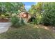 Two-car garage with an exterior staircase surrounded by mature trees and landscaping at 5775 Lakeshore Dr, Buford, GA 30518