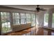 Bright sunroom featuring large windows, hardwood floors, and a ceiling fan with easy access to the outdoors at 5775 Lakeshore Dr, Buford, GA 30518