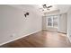 Primary bedroom showcasing wood floors, tray ceiling, ceiling fan, and bright window at 905 Freedom Ln, Roswell, GA 30075