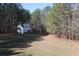 Spacious backyard with a detached garage surrounded by lush greenery and mature trees at 2100 Indian Shoals Dr, Loganville, GA 30052