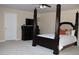 Cozy bedroom with neutral carpeting, a dark wood four poster bed and matching chest of drawers at 2100 Indian Shoals Dr, Loganville, GA 30052