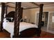 Spacious main bedroom with dark wood floors, a four post bed and attached bathroom at 2100 Indian Shoals Dr, Loganville, GA 30052