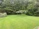 Expansive green backyard with lush lawn, flowering trees, and mature greenery, perfect for outdoor activities at 4850 Guilford Forest Sw Dr, Atlanta, GA 30331