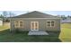 Back of the house with a small patio, verdant lawn, and tidy landscaping at 8588 Preakness Pass, Lithonia, GA 30058