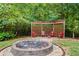 Backyard with a stone fire pit area, trellised seating, and mature trees offers a private and relaxing outdoor space at 52 Olivia Ct, Palmetto, GA 30268