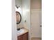 Bathroom with a vanity featuring brown cabinets, an oval mirror and a white door at 52 Olivia Ct, Palmetto, GA 30268