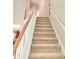 Carpeted staircase with white railing and wood banister, offering safe and stylish access to the upper levels of the home at 52 Olivia Ct, Palmetto, GA 30268