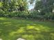 View of the green lawn surrounded by lush shrubbery and trees, with a house partially visible in the background at 6214 Ripple Way # 91, South Fulton, GA 30349