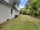 Backyard showing the side of the house with a white brick exterior, green lawn, and lush surrounding greenery at 1909 Meadow Ln, Decatur, GA 30032