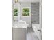 Modern bathroom with a bright vanity, gray marble tiled wall, and a window offering a green view of the outdoors at 1909 Meadow Ln, Decatur, GA 30032